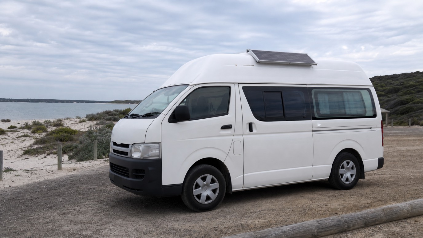 A white high-roof Toyota HiAce campervan parked at a Western Australian coastal campground.