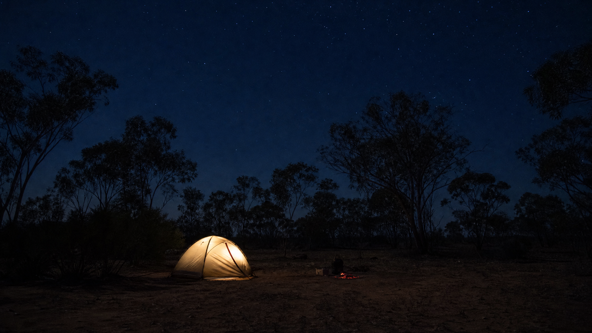 A ground tent glowing warmly at an outback Western Australia campsite under a starry sky