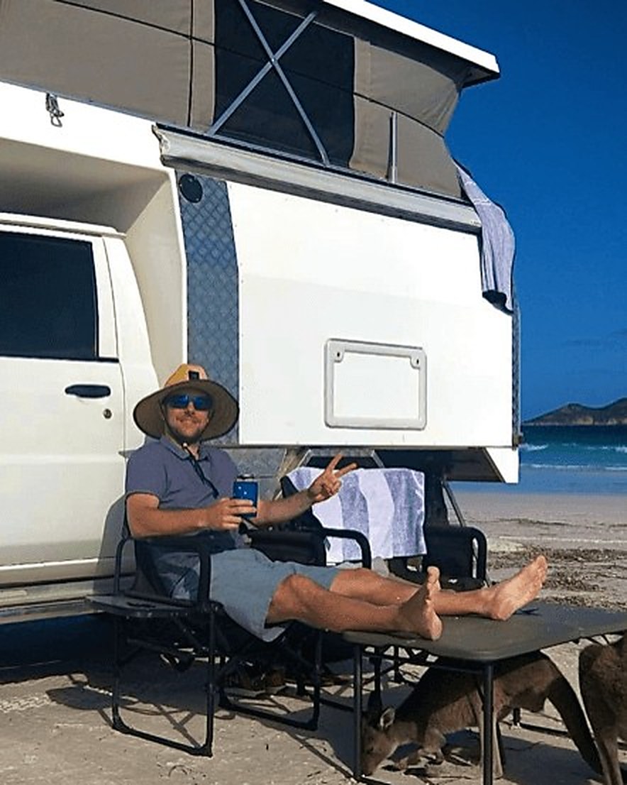 Dorian, owner of Offgrid Campers WA, beside the camper at Lucky Bay with a kangaroo nearby